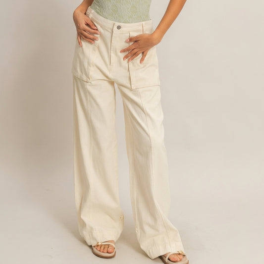 Woman wearing wide beige pants, green top, sandals; light background.