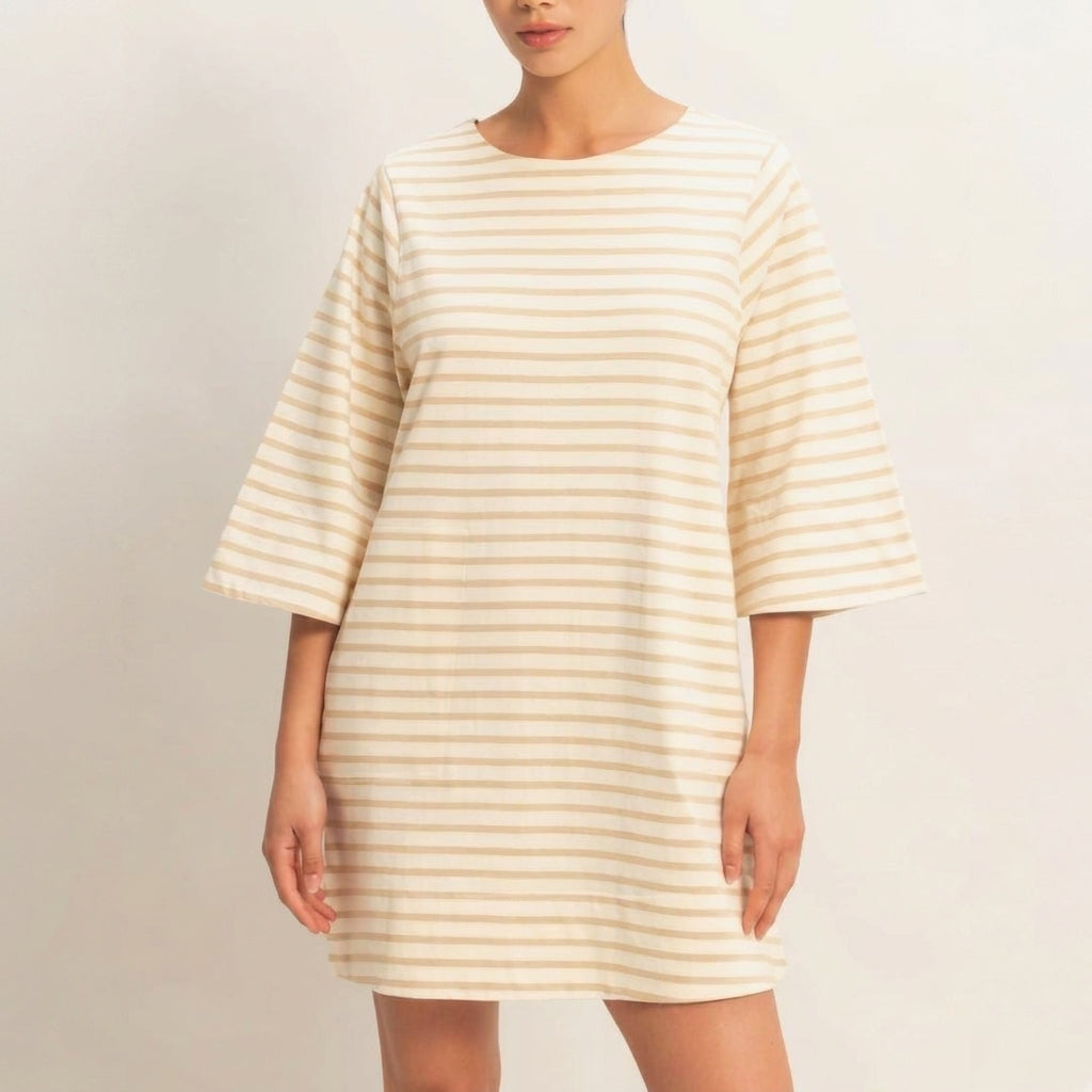 A person in a beige striped, loose-fitting dress with wide sleeves.