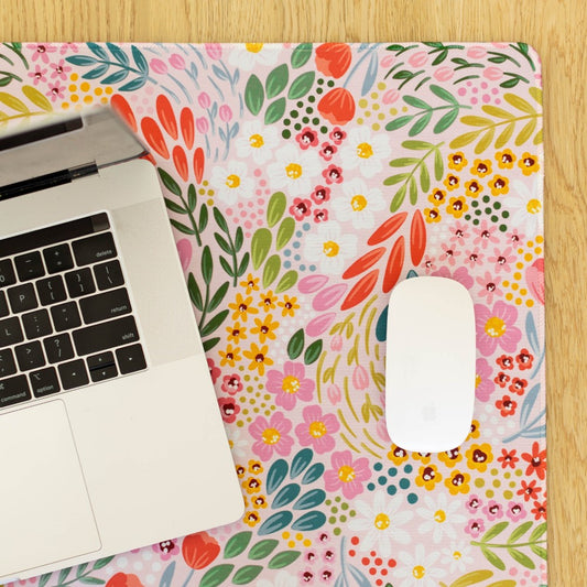 Laptop and mouse on a vibrant floral desk mat.