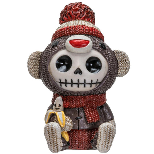Skeleton monkey figurine with knitted hat, scarf, and banana.