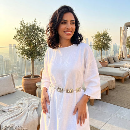 Woman in white dress on a rooftop terrace at sunset.