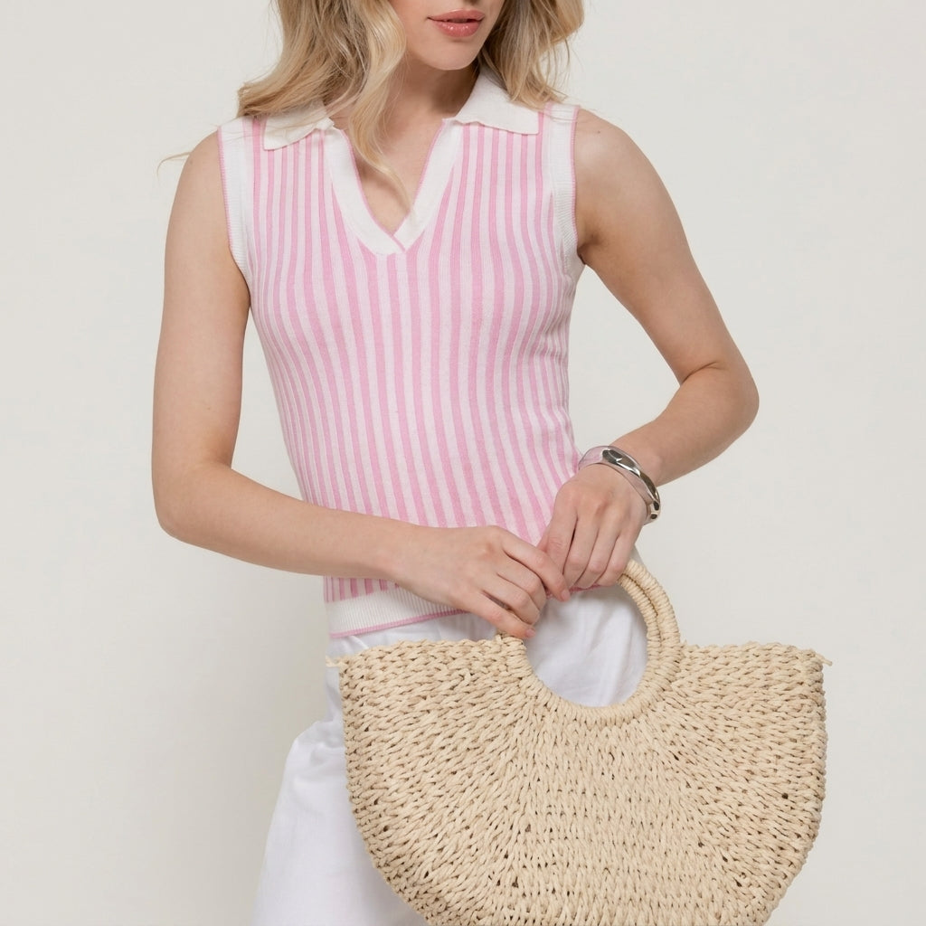 Person in pink striped top holding a straw handbag.