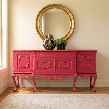 Vintage pink sideboard with gold mirror and decor.