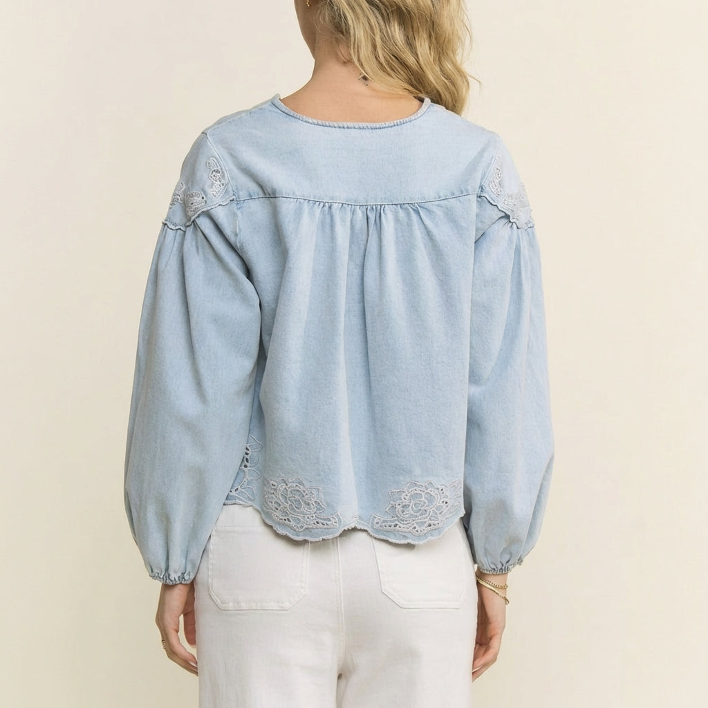 Woman in light blue blouse with floral embroidery, facing away.
