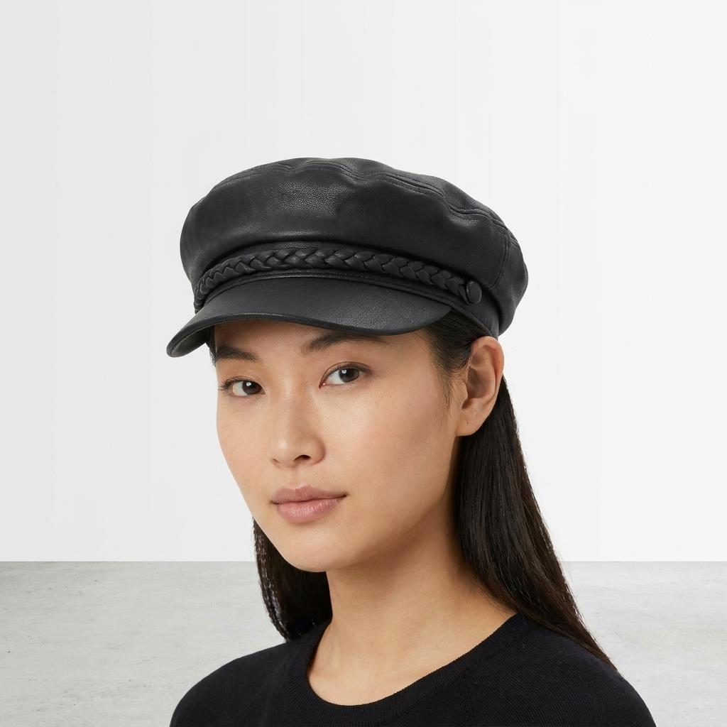 Person wearing a black leather cap with braided trim, neutral background.