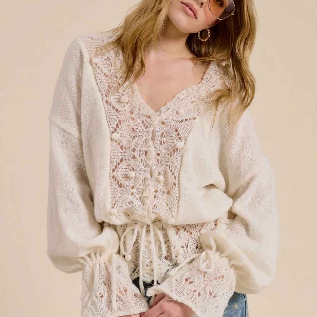 Woman in a cream crochet top and sunglasses against a beige background.
