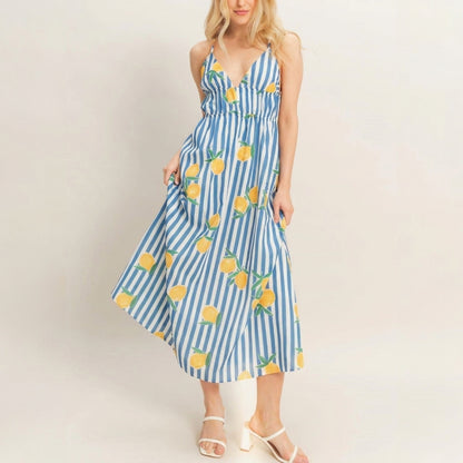 Woman in a lemon-patterned blue and white striped dress with white heels.