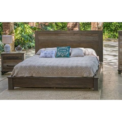Rustic wooden bed outdoors with cozy pillows and greenery around.