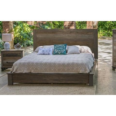 Rustic wooden bed outdoors with cozy pillows and greenery around.