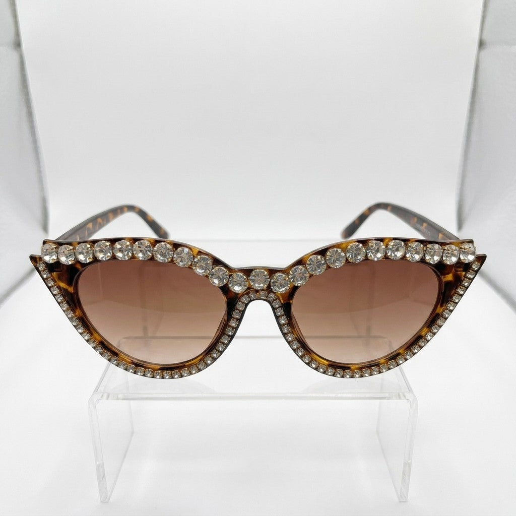 Rhinestone-studded cat-eye sunglasses on display stand.