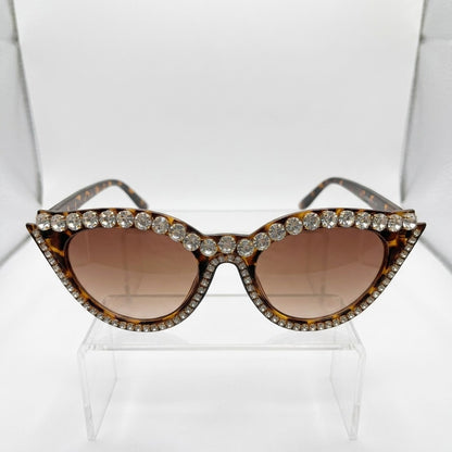 Rhinestone-studded cat-eye sunglasses on display stand.