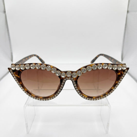 Rhinestone-studded cat-eye sunglasses on display stand.