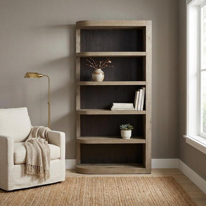 Cozy reading nook with an armchair, lamp, and wooden bookshelf by a window.
