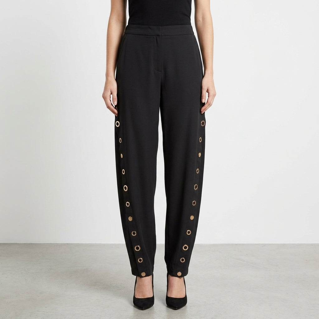 Black pants with side grommet detail, styled with black heels.