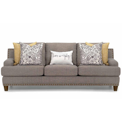 Gray sofa with patterned cushions and "live simply" pillow.