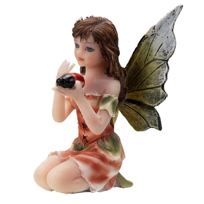Kneeling fairy figurine holding a ladybug, wearing an orange dress.