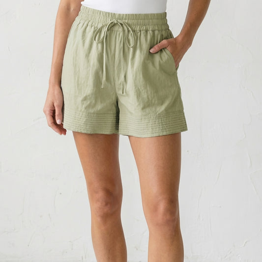 Person wearing light green shorts with a drawstring waist.