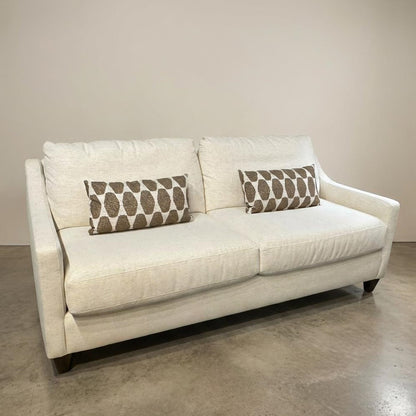 Beige sofa with patterned cushions on a polished concrete floor.