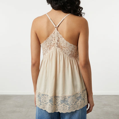 Woman in lace-trimmed beige top, facing away, casual style.