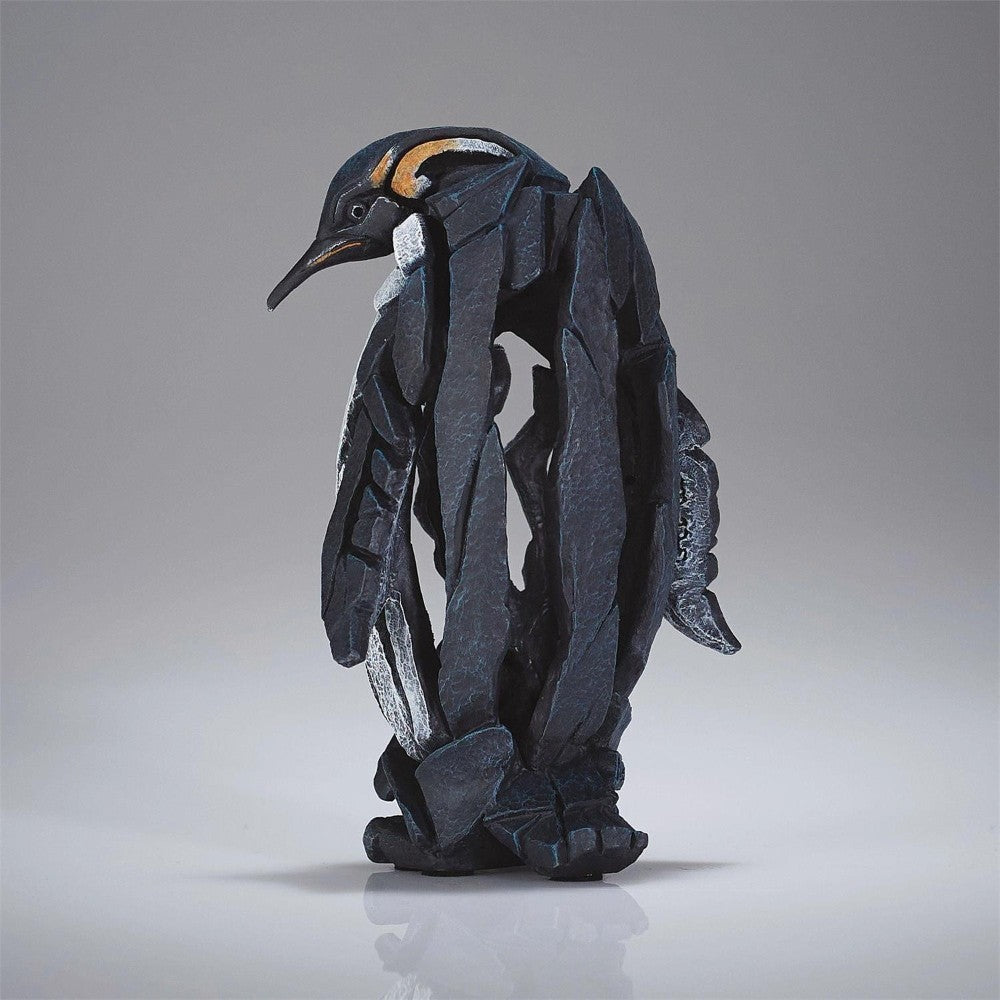 Abstract penguin sculpture made of angular, black stone pieces.