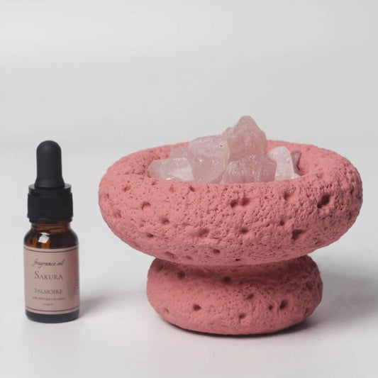 Pink stone bowl with crystals and a bottle of Sakura fragrance oil.