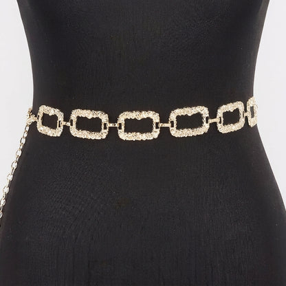 Gold chain belt with textured, rectangular links on a black mannequin.