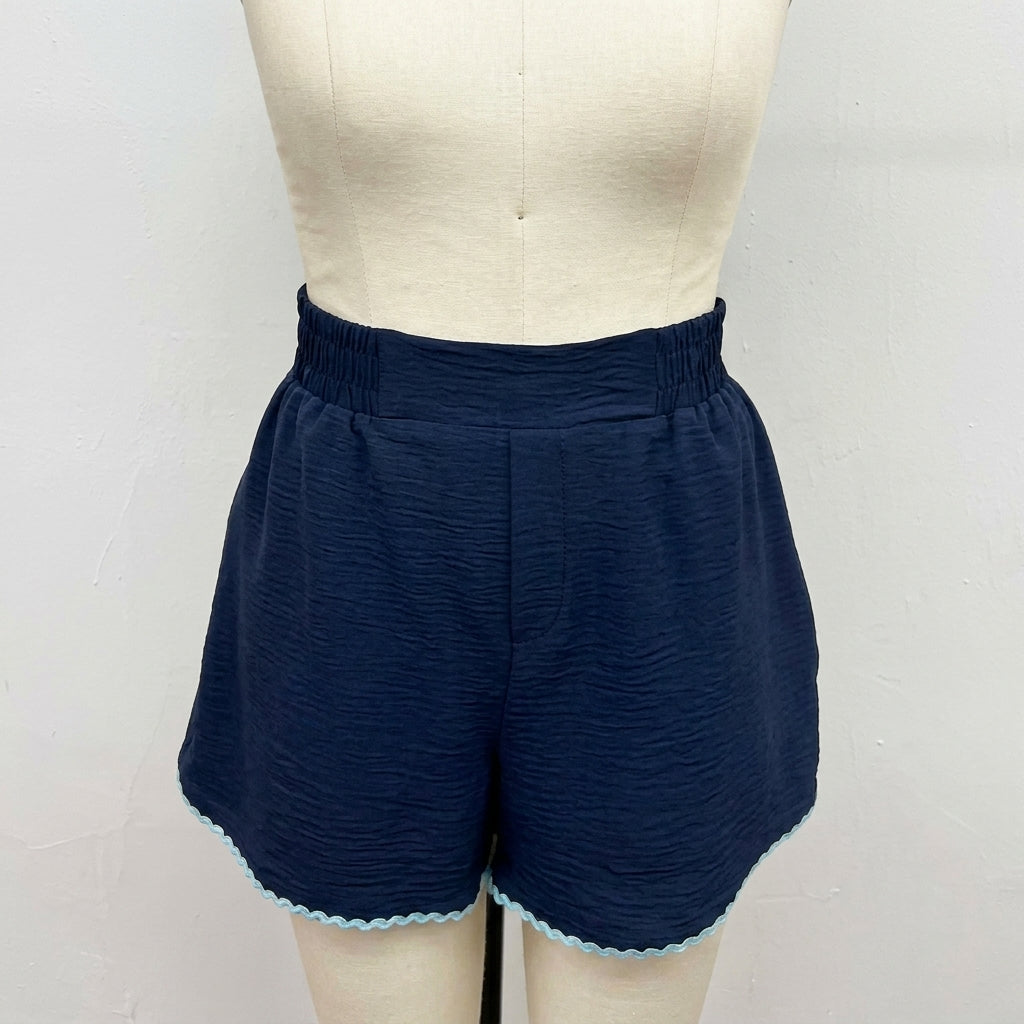 Navy blue shorts with wavy hem on a mannequin.