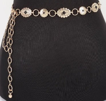 Gold chain belt with floral designs on a black mannequin.