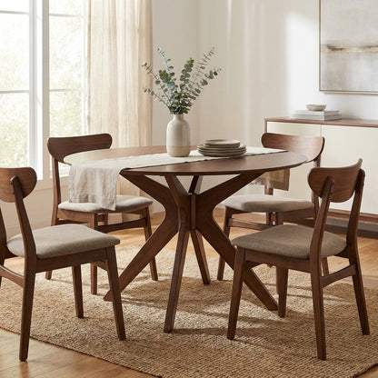 Mid-century dining set with vase centerpiece on a textured rug, softly lit by natural light.