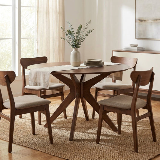 Mid-century dining set with vase centerpiece on a textured rug, softly lit by natural light.