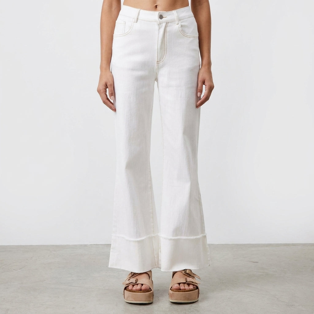 Woman in white flared jeans and beige platform sandals.