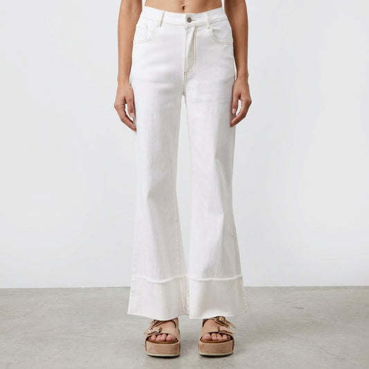 Woman in white flared jeans and beige platform sandals.
