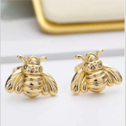 Gold bee-shaped earrings on a white surface.