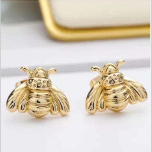 Gold bee-shaped earrings on a white surface.
