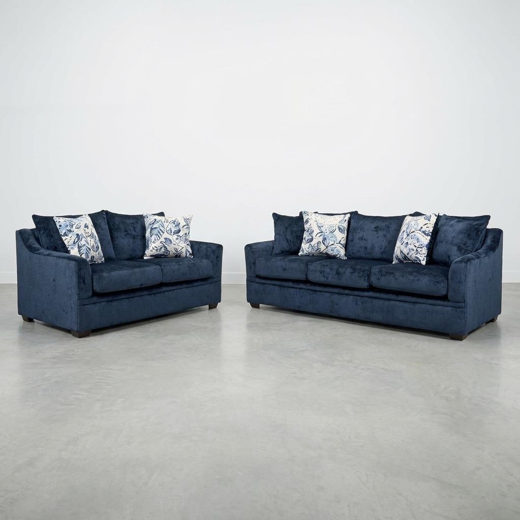 Two blue sofas with patterned pillows on a grey floor.