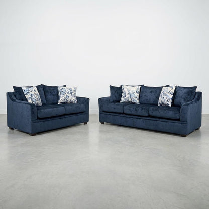 Two blue sofas with patterned pillows on a grey floor.