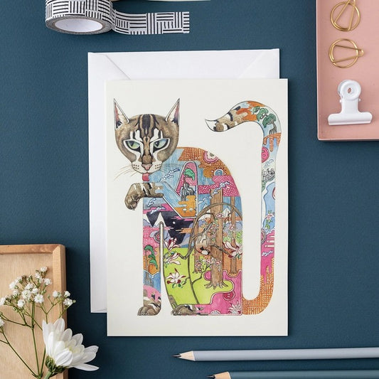 Colorful cat illustration on a card with stationery items around.