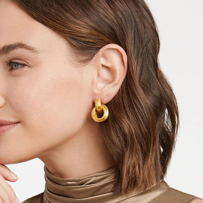 Close-up of a woman wearing gold double-hoop earrings.