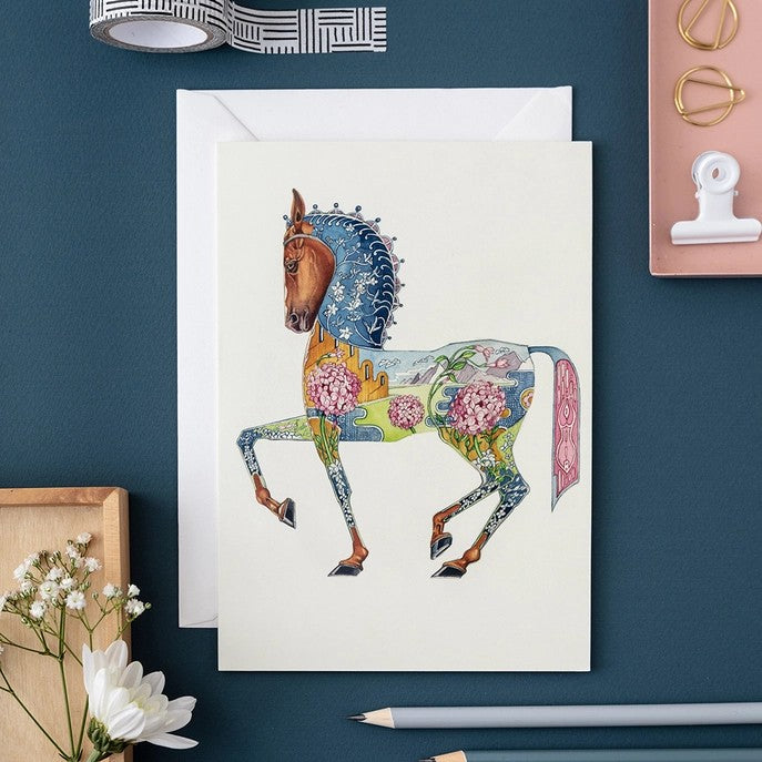 Colorful horse card on a blue desk with stationery.