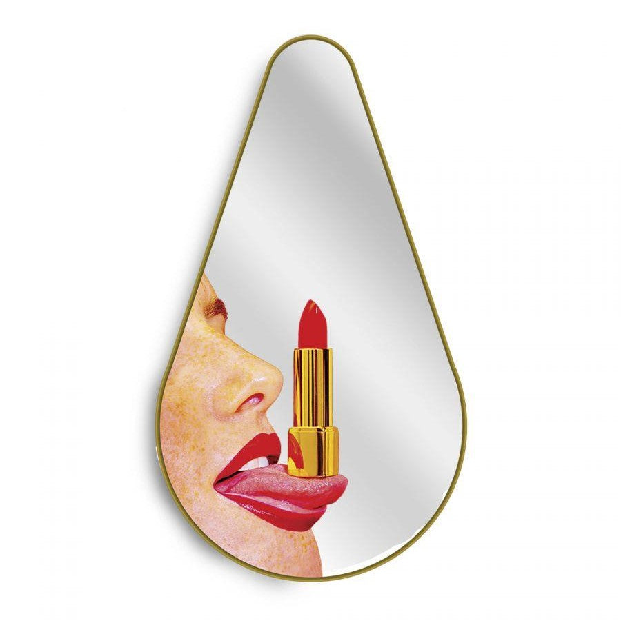 A teardrop mirror reflects a woman with lipstick, tongue out playfully.