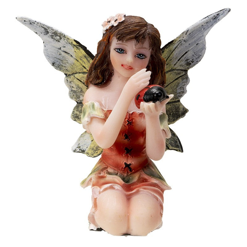 Fairy figurine with wings holding a ladybug, wearing a floral dress.