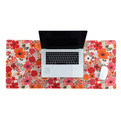 Laptop and mouse on a colorful floral desk mat.