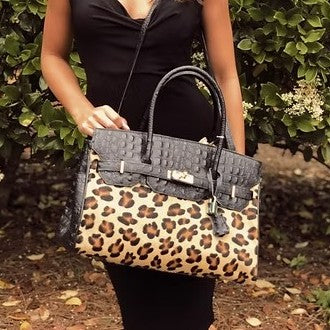 Woman holding a leopard-print and black handbag outdoors.
