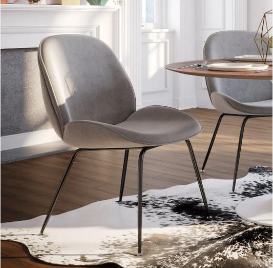 Modern gray chair on cowhide rug in stylish dining area.