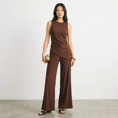 Person in a stylish brown outfit holding a small clutch.