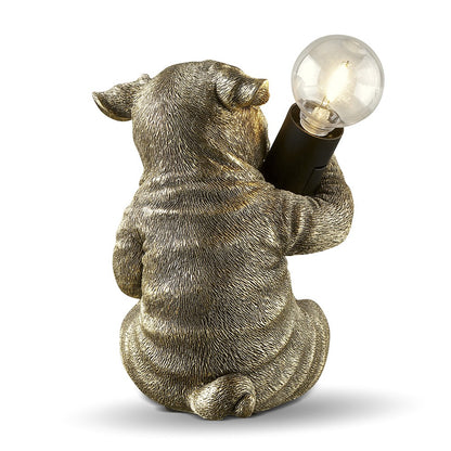 Pig-shaped lamp holding a glowing bulb.