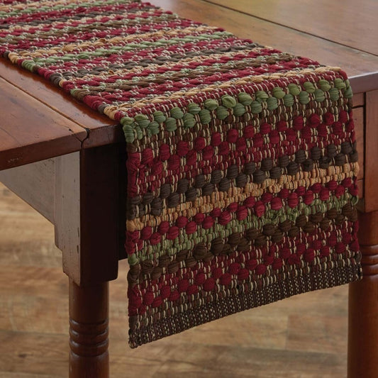 Woven table runner with autumn colors on a wooden table.