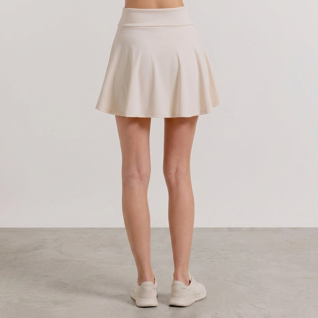 Ivory pleated mini skirt worn by a woman.