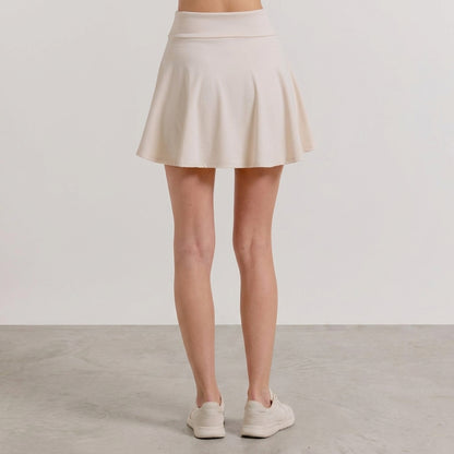 Ivory pleated mini skirt worn by a woman.
