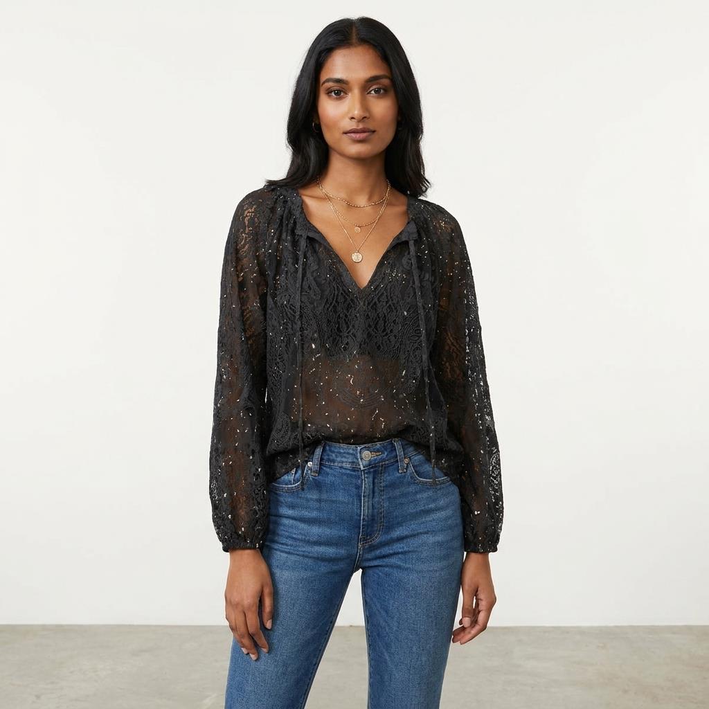 Woman in sheer black top and jeans, standing confidently against a plain background.